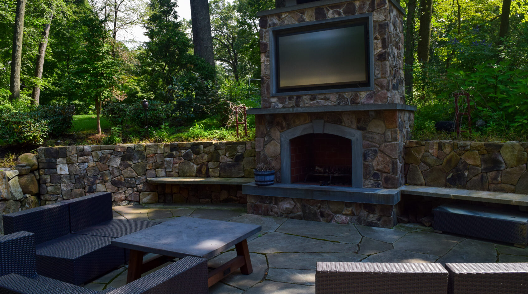 Beautiful stone facade on an outdoor fireplace complete with a TV and outdoor seating